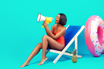 Amazing offer. Young black woman in swimsuit sitting in lounge chair, shouting into megaphone,...