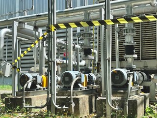 A complex array of industrial pipes, pumps, and motors in a factory or power plant, marked by a...