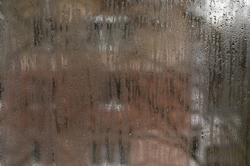 Abstract art of nature: water drops create random patterns on fogged window. Glass transforms into...