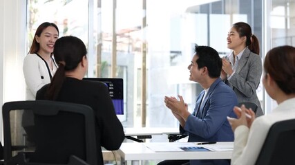 Business team applauding colleague after successful presentation.