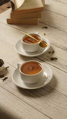 cup of tea, tea being poured into a transparent and white tea cup, teapot and tea cup with floral...