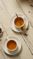 cup of tea, tea being poured into a transparent and white tea cup, teapot and tea cup with floral...
