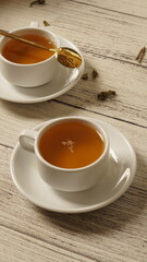 cup of tea, tea being poured into a transparent and white tea cup, teapot and tea cup with floral...