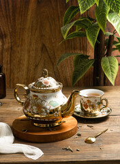 cup of tea, tea being poured into a transparent and white tea cup, teapot and tea cup with floral motif, darmkmood tea photo display