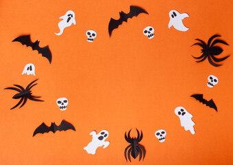 Halloween composition of spiders, bats, skulls and ghosts on orange background.