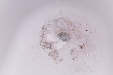 there is dirty foam in bathroom sink and water drains into the sewer after washing. Minimalist view...