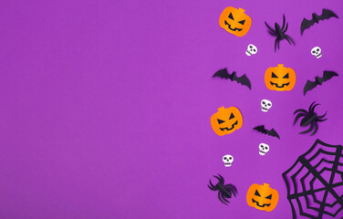 halloween concept, paper figures of pumpkins, bats, spiders and skulls on a purple background