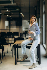 Modern Businesswoman Sitting in a Stylish Office Holding a Laptop