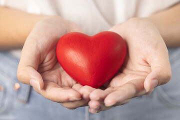 woman hands giving a red heart, red heart in young girl hands , health care, organ donation, family life insurance, world heart day, brain stroke. love concept.
