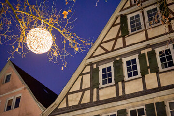 Christmas decoration against a blue night sky. Half-timbered houses in the background. Low angle view.