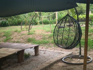 Cozy outdoor seating area with a hanging chair surrounded by greenery and recreational space