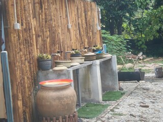 Outdoor water station with clay pots and bamboo backdrop in a lush garden setting