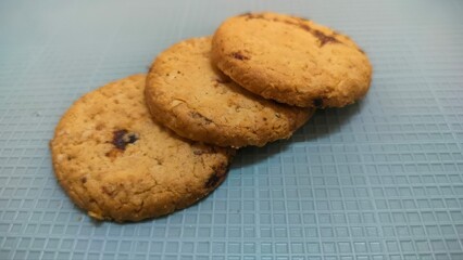 Three freshly baked cookies arranged on a textured surface, with a soft focus background