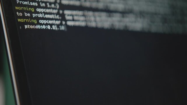 A close-up shot of a computer's command line interface. A blinking cursor and running text show a system process or script executing. Concept of hacking or software development.