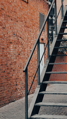 Outdoor straight metal staircase attached to urban industrial building facade