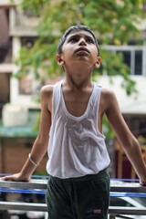 Little kid playing in summer rain in house balcony, Indian smart boy playing with rain drops during...