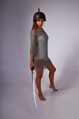 Barefoot slender woman in chainmail and medieval Asian helmet holding traditional Japanese sword...