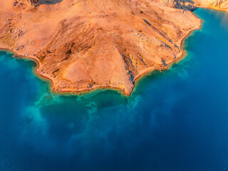 Rucica beach in Metajna on Pag island curved shoreline, crystal-clear turquoise sea, sunlit barren...