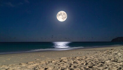 Full moon over tranquil ocean beach at night; moonlight reflects on the water