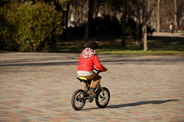 A boy rides a bicycle in the park on a sunny spring day. Children's activity for the harmonious development of the teenage generation. Game in the fresh air. Equilibrium on a two-wheeled transport