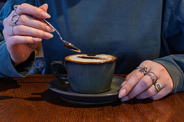 Hot coffee with milk and foam, cappuccino or latte in a beautiful and cozy dark blue mug. A young...