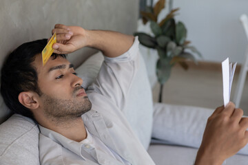 Stressed and headache asian man with large bills or invoices no money to pay to expenses and credit...