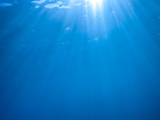 Dark blue ocean surface seen from underwater. Abstract waves underwater and rays of sunlight...