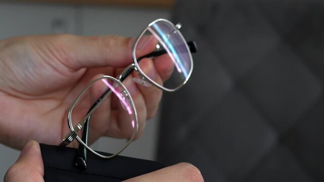 A case for storing glasses in a person's hands.
A man stores glasses in a shockproof case.
Glasses for vision are in a box
