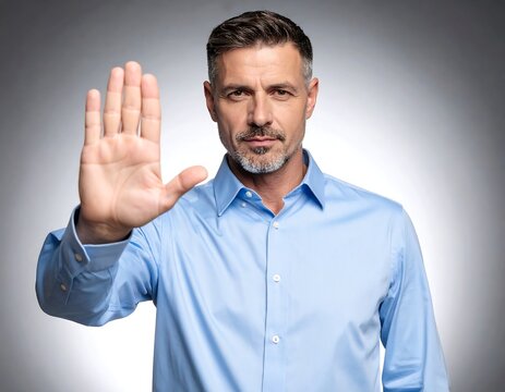 A middle-aged man in a light blue shirt holds his hand up in a stop gesture