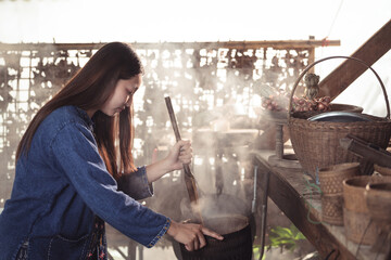 A close-up captures a woman stirring a traditional meal, with fresh ingredients like shallots...