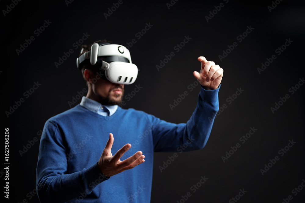 Poster man engaged in virtual reality experience while gesturing with hands in a dark environment