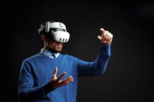 Man engaged in virtual reality experience while gesturing with hands in a dark environment