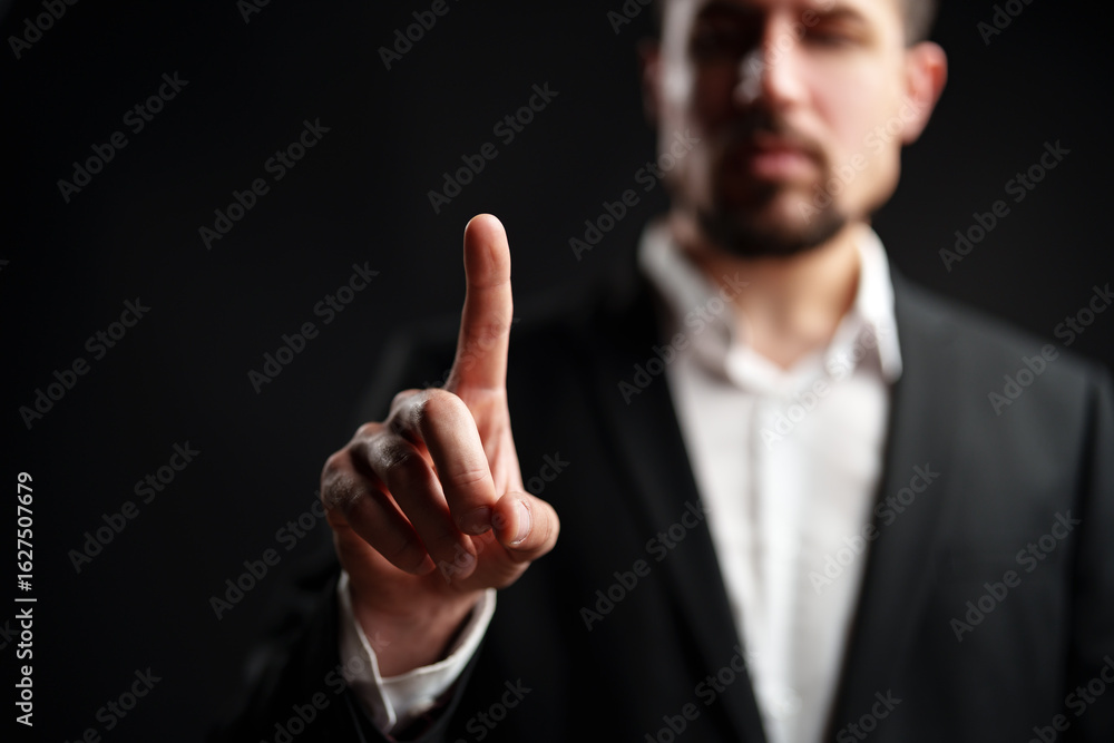Poster man in a suit holds one finger up against a dark background to convey a message or emphasize a point