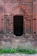 Old brick arches frame a weathered wooden door in an abandoned building in Bangladesh.