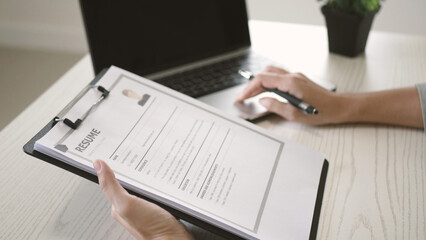 Businesswoman is reading a resume to evaluate a job applicant. Sitting reading a resume to hire...