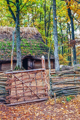Longhouse in a tree grove with a wooden gate
