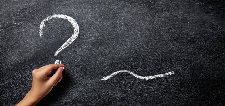 The hand writing a question mark on a chalkboard surface. - Powered by Adobe