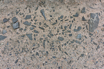 Close-up view of a gravel pathway showing various stone fragments embedded in sand, illustrating natural textures and colors.