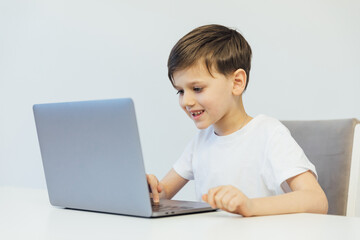 Boy working at desk with study laptop at school