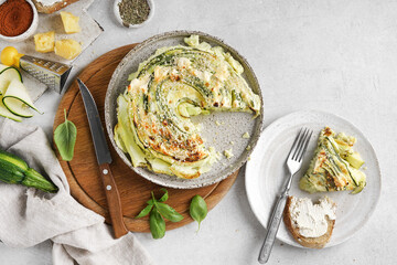 Vegetable green zucchini round pie with piece on the ceramic plate on white background, top view, copy space