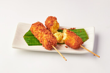 Crispy deep fried cheese sticks served on white plate with banana leaf garnish, showcasing golden...