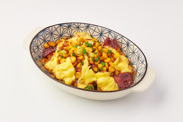 Delicious baked dish featuring melted cheese, sweet corn, and savory meat slices, garnished with green onions, served in decorative ceramic bowl