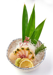 Fresh sashimi scallops served on bed of ice with garnishes of lemon slices, wasabi, shredded radish, and green leaves, creating visually appealing and appetizing presentation