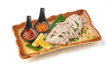 Steamed fish fillet served on decorative plate with fresh herbs, lemon wedges, and two spicy dipping sauces, creating vibrant and appetizing presentation