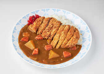 Plate of Japanese curry rice with crispy fried chicken cutlet, served with chunks of carrots, potatoes, and garnish of pickled red ginger, creating comforting and flavorful meal