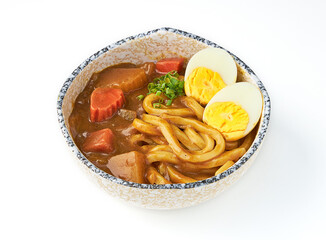 Bowl of Japanese curry udon with thick noodles, rich curry sauce, tender carrots, potatoes, and boiled egg, garnished with green onions, served in ceramic bowl