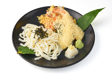 Crispy tempura shrimp and vegetables served with udon noodles, garnished with seaweed, grated radish, and wasabi on black plate, creating delicious and traditional Japanese dish