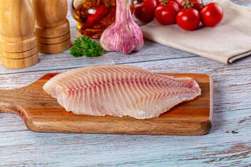 Raw tilapia fish fillet over board