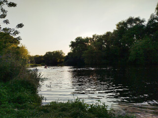 Serene river view during sunset with kayaker © Nicolae G Talmach