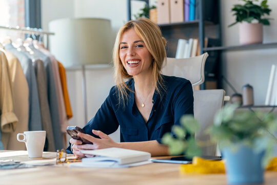 Fashion designer working in stylish workspace with clothing and accessories